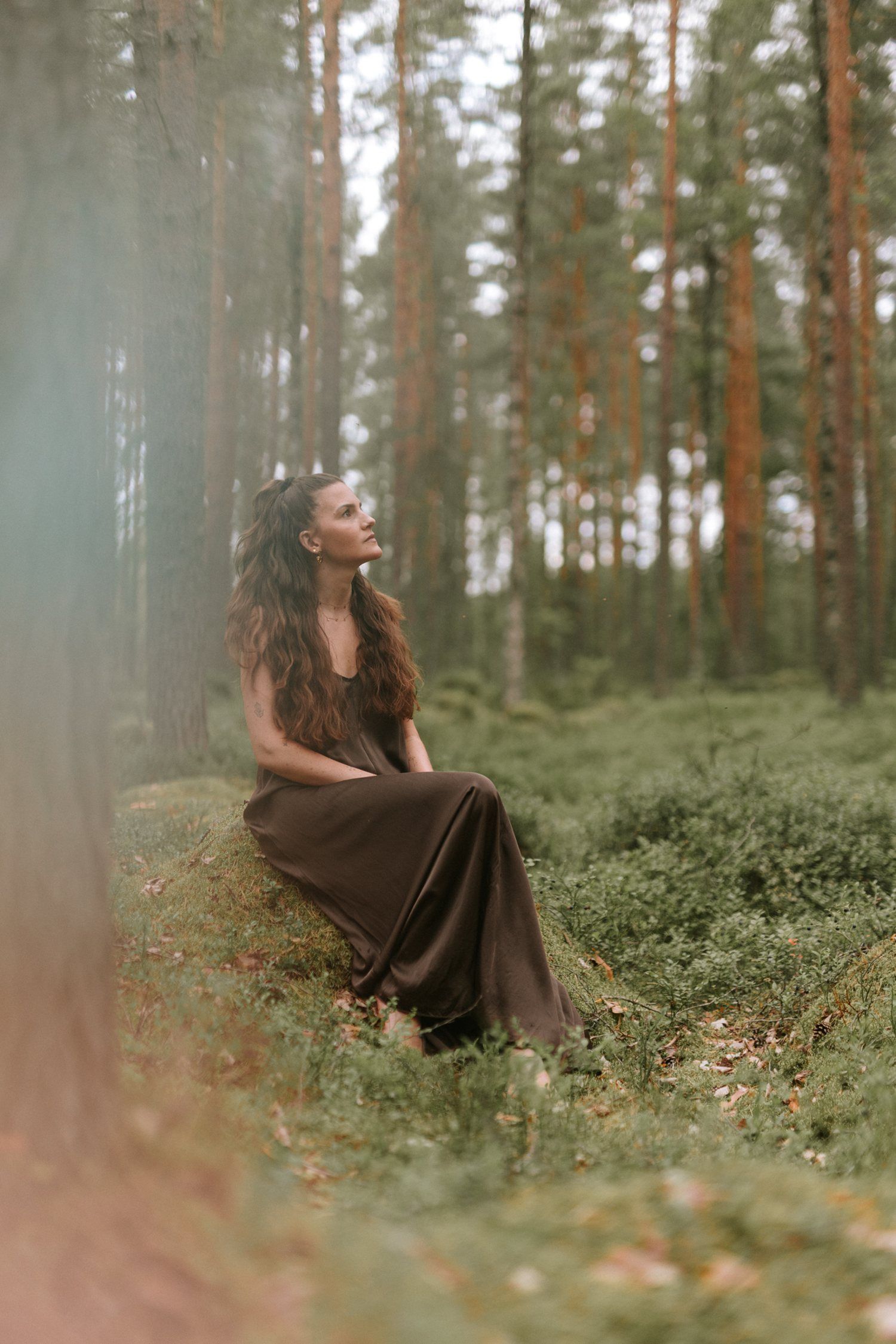 Selina sitzt im Kiefernwald und schaut nach oben